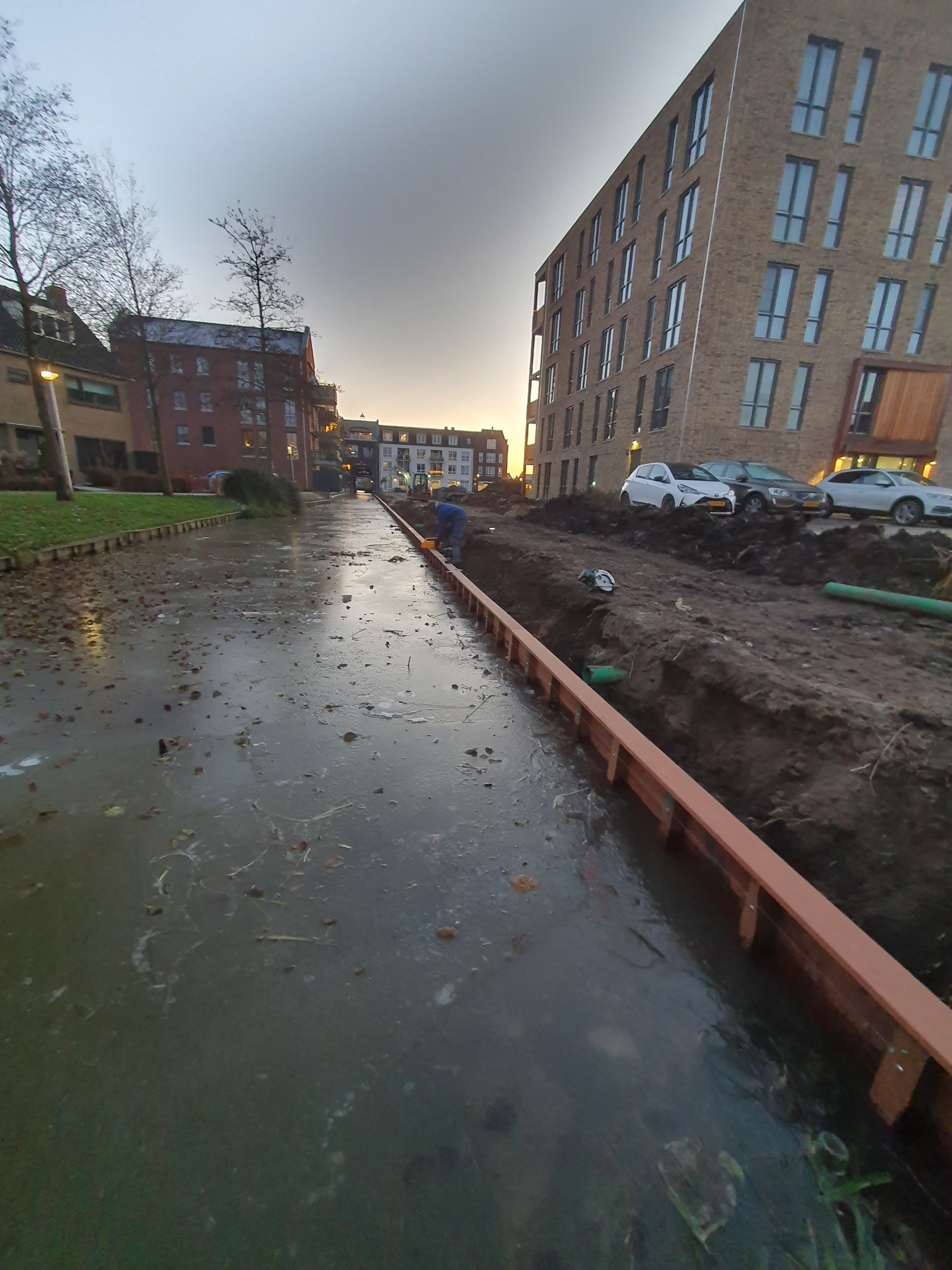 Houten beschoeiing langs de oever van een kanaal als afwerking van de waterkant.