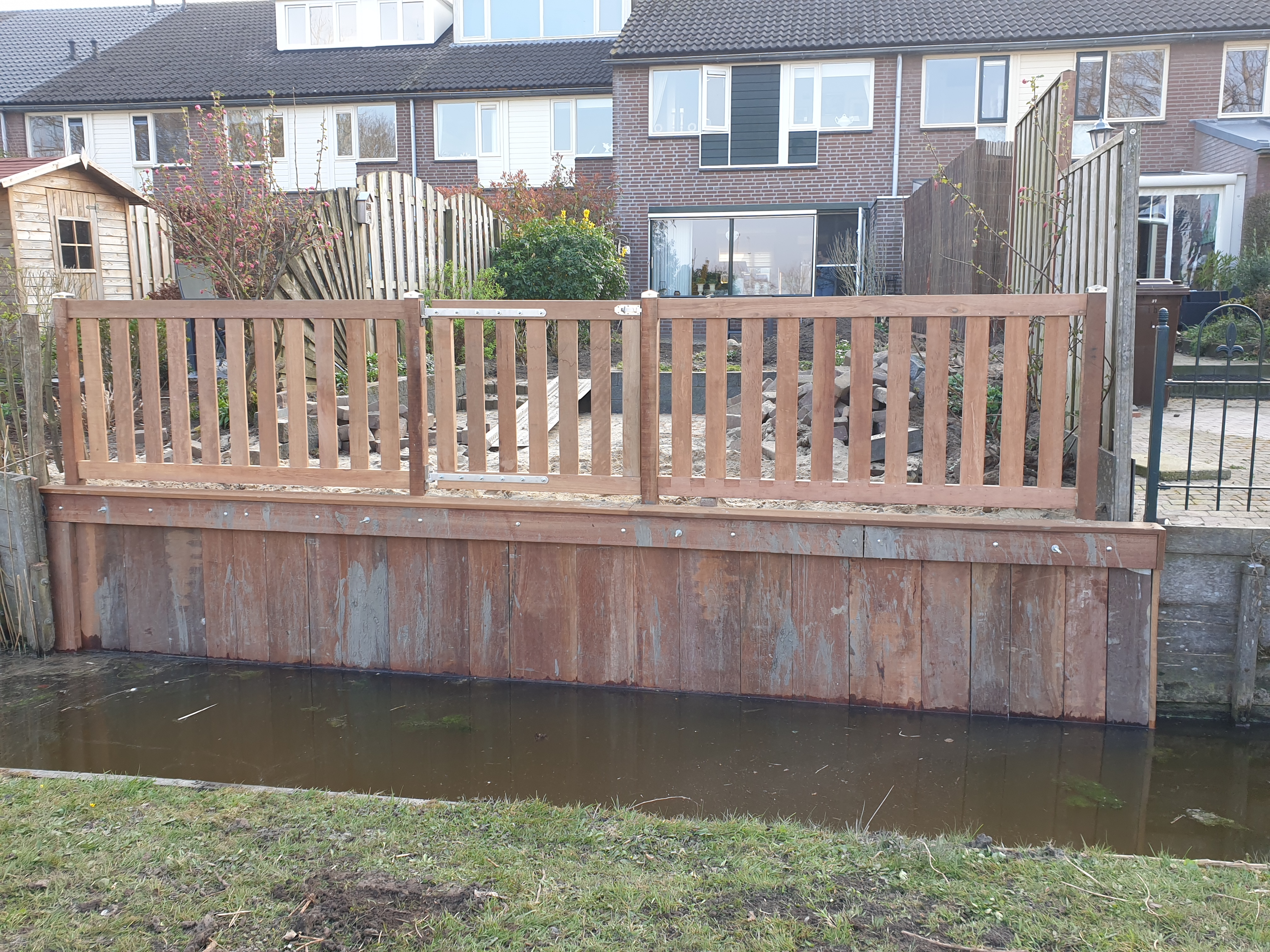 Beschoeiing met hek bij een achtertuin aan het water.